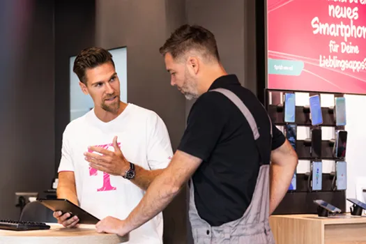 Beratung im Handyshop: Mitarbeiter zeigt Smartphone-Angebote am Tablet.